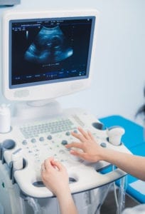 Hands on an ultrasound machine at modern clinic.